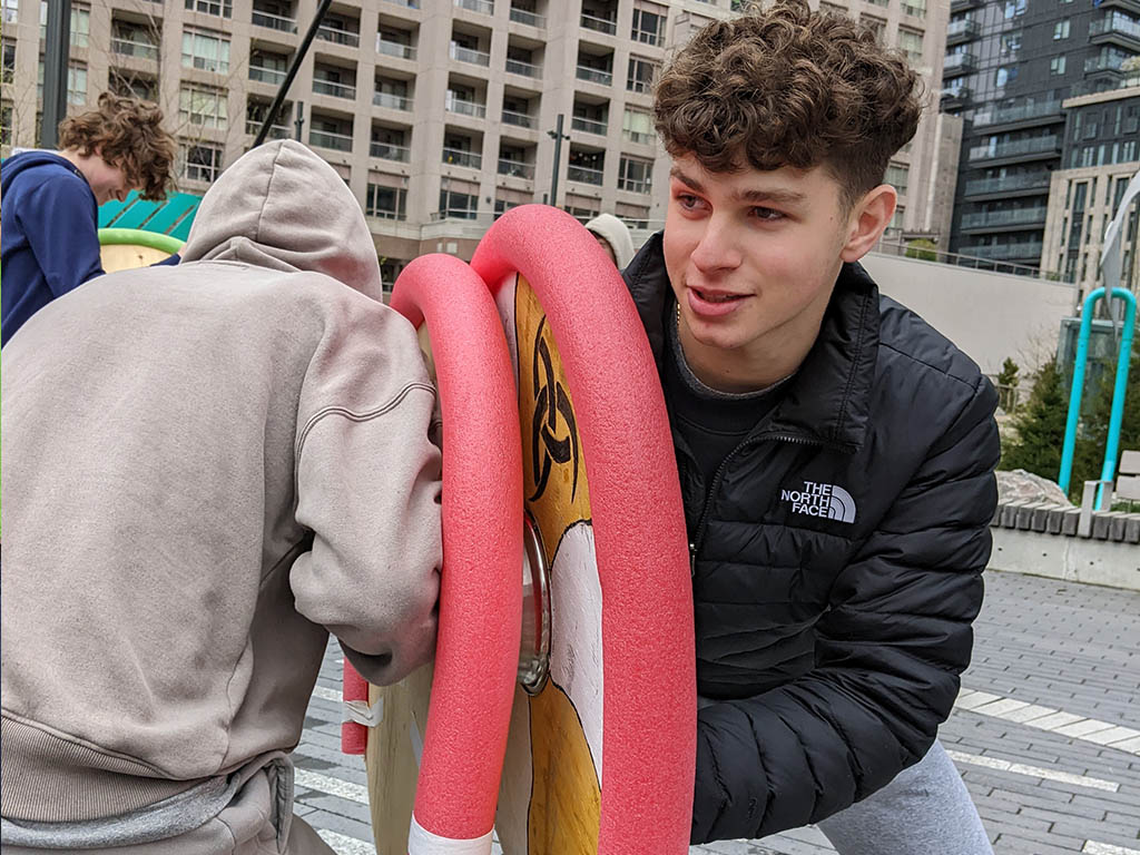 The Grade 12 Adventures in World History class engaged in some hands-on-experiential learning in the park near YMCA Academy. Students have been learning about the adventures of Norwegian, and Danish societies of the Viking Age roughly one thousand years ago.